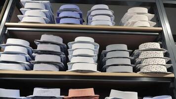 Stacked folded shirts in a store. Neatly stacked folded shirts in various colors and patterns on display shelves in a men's clothing store. video