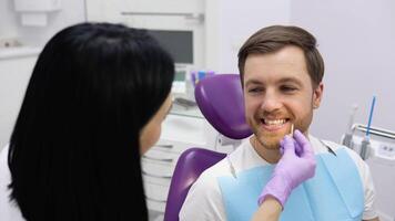 Dentist selecting tooth color from special scale. Selection of the correct tooth color for professional cosmetic bleaching at the dentist video