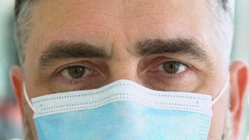 Close up senior doctor with face mask preparing surgery intervention medical clinic. Selective focus on one eye. S3niorlife and Be H3althy concept video