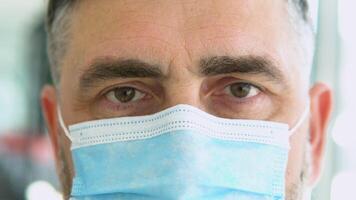 Close up senior doctor with face mask preparing surgery intervention medical clinic. Selective focus on one eye video