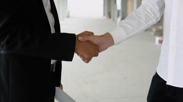 Close up of multiethnic people handshake on construction of building or office. Two engineer shaking hands with deals and congratulations on success video