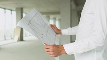 Engineer builder at construction site with blueprint, close up video