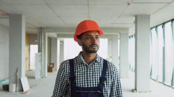 Indian asian builder engineer worker in uniform and helmet walking at construction site of skyscraper video