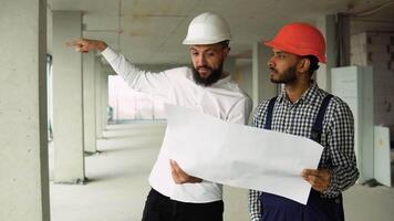 Architect is explaining to indian builder the plan of construction. The foreman pointing at building with seriousness video