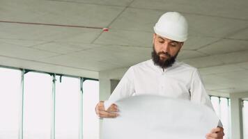 ásia engenheiro bonito homem ou arquiteto com branco segurança capacete olhando construção plano dentro construção local do escritório Centro video