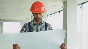 Indian pakistani worker builder engineer in uniform looking construction plan in construction site video