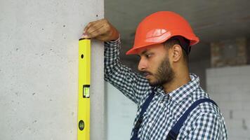 Indian engineer measures of the vertical deviation of the wall. Bubble level ruler close up view, measuring and leveling concept video