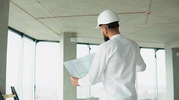 Arab engineer builder at construction site of office center with blueprint video