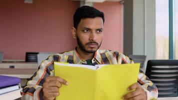 Thoughtful Indian or Pakistani student reads a book in a university library. Preparing to the exams video