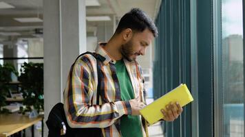 Portrait of Indian clever student with open book reading it in college library video
