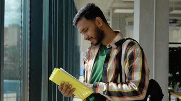 Portrait of Indian clever student with open book reading it in university video