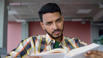Indian or Pakistani student reads a book in a university library. Preparing to the exams video