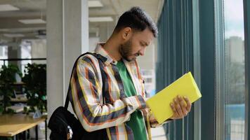 Portrait of Indian clever student with open book reading it in lecture room video