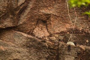 Dark red orange brown stone with cracks Closeup of uneven mountain surface photo