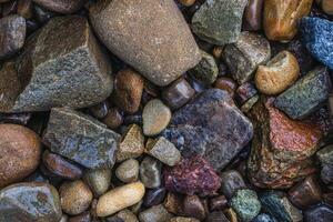 These are wet river pebbles and small round pebbles. Solid background. Top view photo