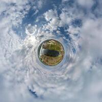 simple tiny planet without buildings in blue sky with beautiful clouds. Transformation of spherical panorama 360 degrees. Spherical abstract aerial view. Curvature of space. photo