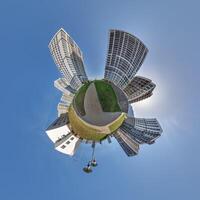 abstract swirling tiny planet spherical panorama of multi-storey buildings of skyscrapers of a residential complex in the form of a butterfly in blue sky photo