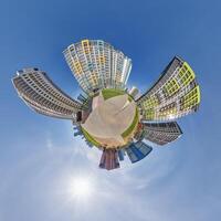 abstract swirling tiny planet spherical panorama of multi-storey buildings of skyscrapers of a residential complex in the form of a butterfly in blue sky photo