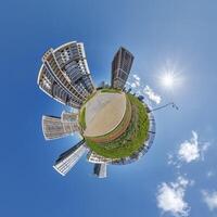 abstract swirling tiny planet spherical panorama of multi-storey buildings of skyscrapers of a residential complex in the form of a butterfly in blue sky photo