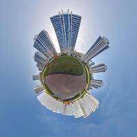 abstract swirling tiny planet spherical panorama of multi-storey buildings of skyscrapers of a residential complex in the form of a butterfly in blue sky photo