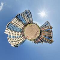 abstract swirling tiny planet spherical panorama of multi-storey buildings of skyscrapers of a residential complex in the form of a butterfly in blue sky photo