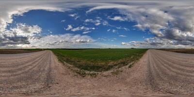 hdri 360 panorama on wet gravel road among fields in spring nasty day with storm clouds before sunset in equirectangular full seamless spherical projection, for VR AR virtual reality content photo