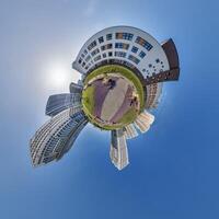 abstract swirling tiny planet spherical panorama of multi-storey buildings of skyscrapers of a residential complex in the form of a butterfly in blue sky photo