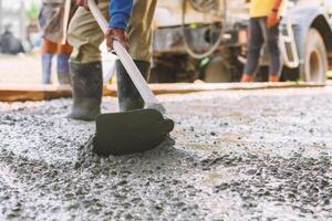 man is using a trowel to spread concrete on a sidewalk photo