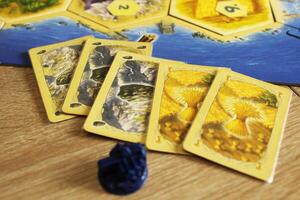 Mozyr, Belarus, April 01 2024. A catan board game buying a city upgrading a settlement to a city for resource maps hay wheat and stone ore photo