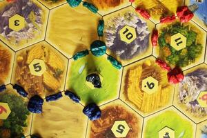 Mozyr, Belarus, April 01 2024. A catan board game blue, green and red chips of players on the field. Blocked resource hex by bandits. The longest highway and the largest army. Extra Points photo