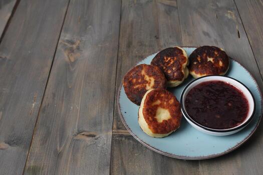 Four cheesecakes on a blue sarrelka with gopberries with red raspberry strawberry jam on a gray background with space for the text of the copyspace. Delicious breakfast photo