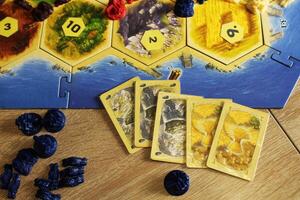 Mozyr, Belarus, April 01 2024. A catan board game buying a city upgrading a settlement to a city for resource maps hay wheat and stone ore photo
