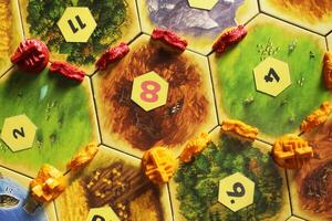 Mozyr, Belarus, April 01 2024. A catan board game red and yellow player tiles of the city settlement road on the map. View from the top photo