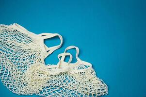 Replacing plastic bags.Taking care of the environment. Empty mesh, awosika on a blue background. photo