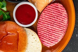 raw burger set cutlet, bun, cheese, tomato sauce, greens fresh cooking appetizer meal food snack on the table copy space food background rustic photo