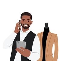 Young tailor talking on smartphone reading notebook at atelier. vector