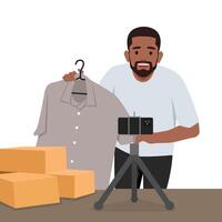 Young man is showing clothes in front of smartphone live streaming at his shop. vector