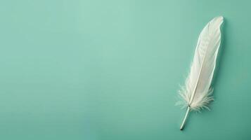 Elegant feather quill pen on a serene mint green background, ideal for creative copyspace photo