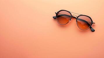 Stylish sunglasses on a peach background with ample copyspace for creative projects photo
