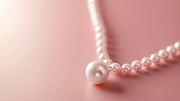 Artistic single pearl necklace on a blush pink background with generous copyspace photo