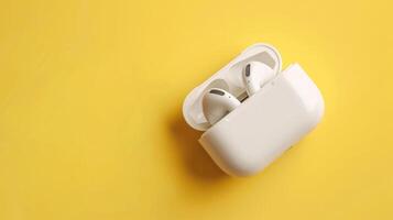 Artistic wireless earbuds on a butter yellow background with abundant copyspace photo
