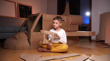 A boy builds a plane out of cardboard. Pilot and airplane game video