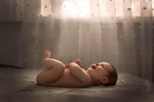 small child on the bed in front of the window photo
