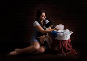 portrait of a girl with a dog washing things in a basin. dark background photo