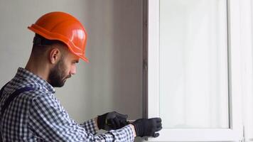 A repairman in uniform and helmet fixing windows in new apartment video