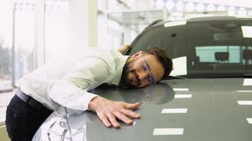 Happy Man Hugging Hood Of His New Car, Joyful Smiling Millennial Guy Dreaming About Buying Vehicle In Auto Showroom, Leaning At Surface Of Luxury Automobile, Closeup Shot video