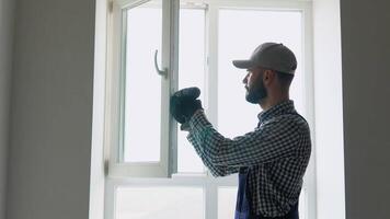Master installer in overalls installing or adjusting pvc windows in office or apartment. Maintenance service video