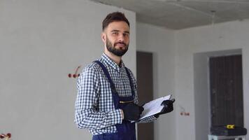 Young foreman builder, engineer or inspector with project documentation at construction site of apartment or office video