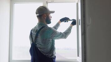 Man in uniform does pvc window installation with a screwdriver video