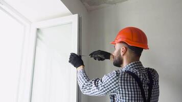 Worker installs and adjusts a new plastic window in house. Repairman regulates Installation and adjustment video